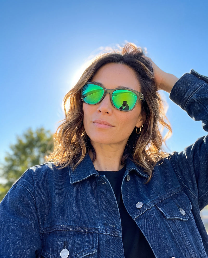 Woman in a denim jacket wearing Vibes Delta 9 sunglasses with green mirror lenses