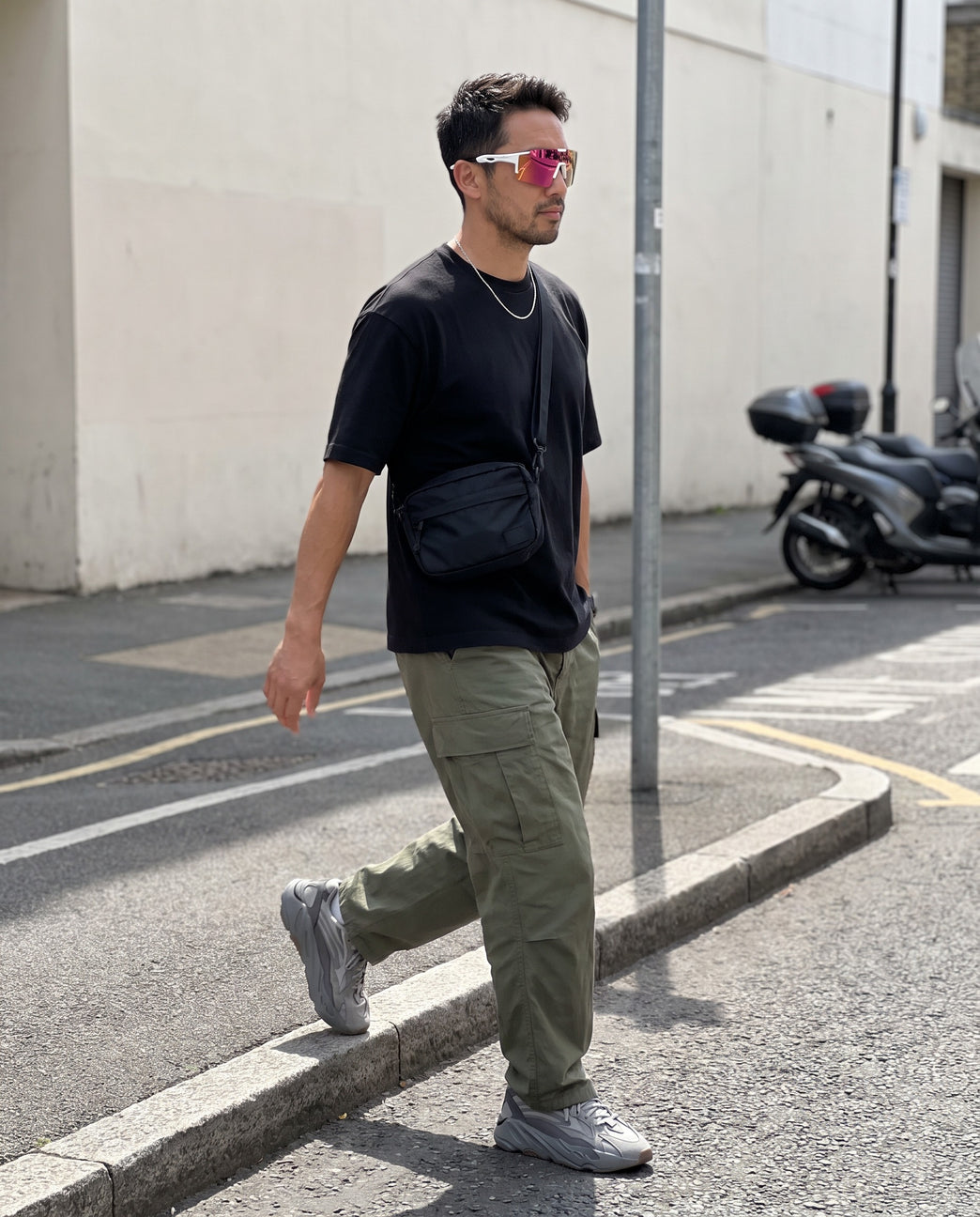 Man walking across a city street wearing Vibes Dial Up sunglasses