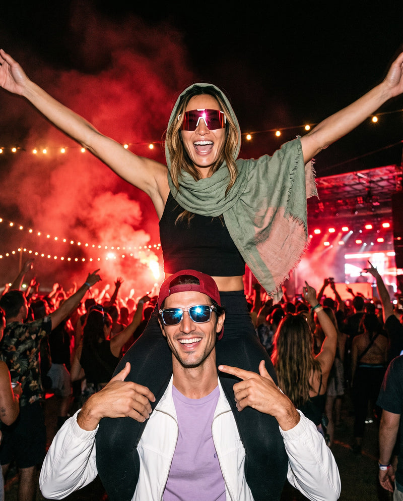 Festival crowd, woman on shoulders in Vibes Dial Up and man in Vibes Marlow sunglasses