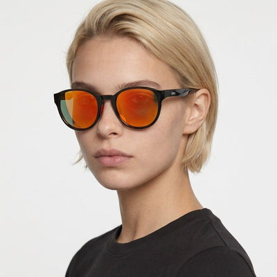 Hollis retro round sunglasses in Orange / Black, orange lens on black frame, worn by a woman, front view