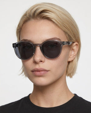 Hollis retro round sunglasses in Grey / Clear Grey, grey lens on clear grey frame, worn by a woman, front view