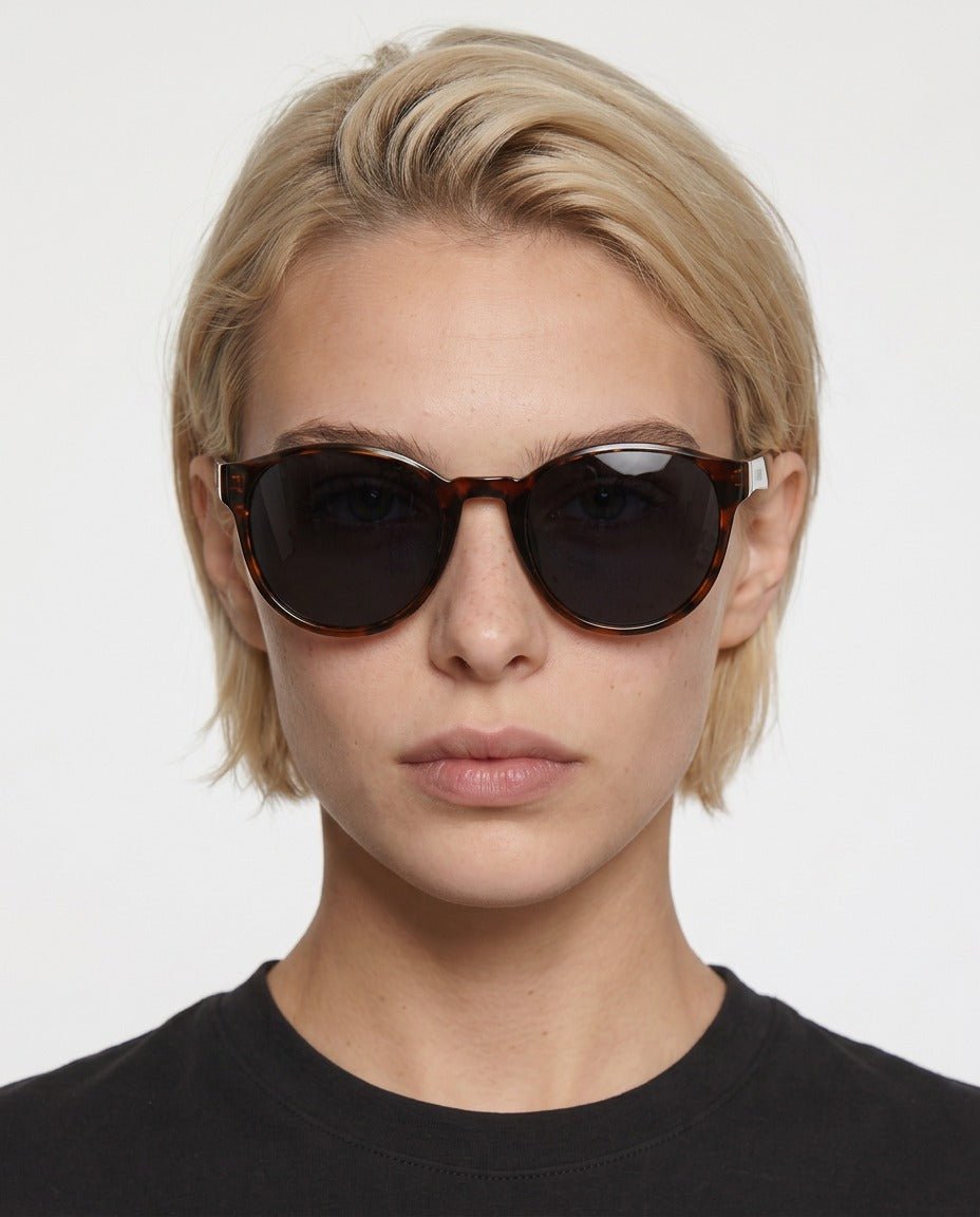 Hollis retro round sunglasses in Black / Tortoise, black lens on tortoise frame, worn by a woman, front view