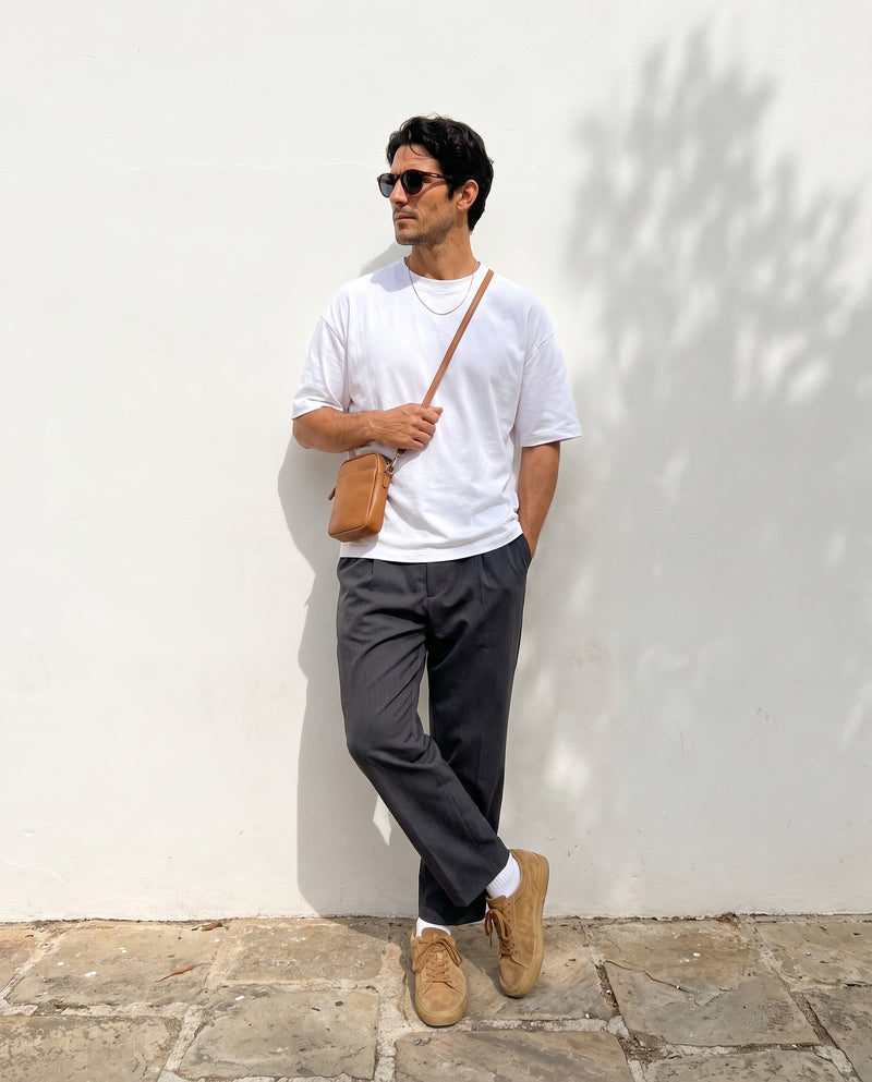 Man leaning on a white wall wearing Vibes Hollis sunglasses