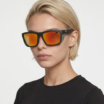 Juno side-shield wrap sunglasses in Orange / Black, orange lens on black frame, worn by a woman, front view