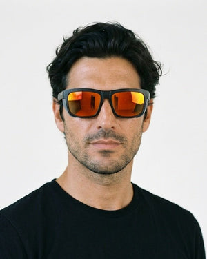 Juno side-shield wrap sunglasses in Orange / Black, orange lens on black frame, worn by a man, front view