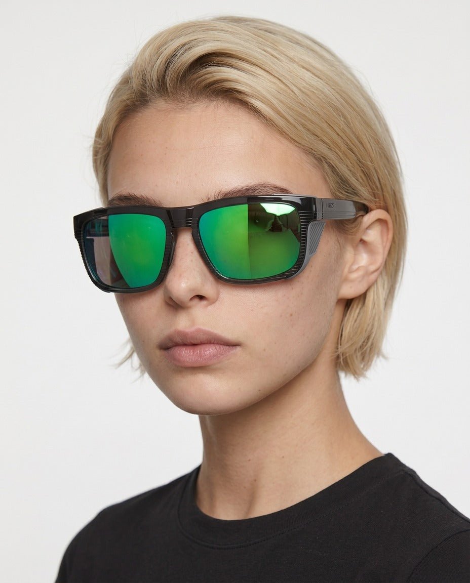 Juno side-shield wrap sunglasses in Green / Black, green lens on black frame, worn by a woman, front view