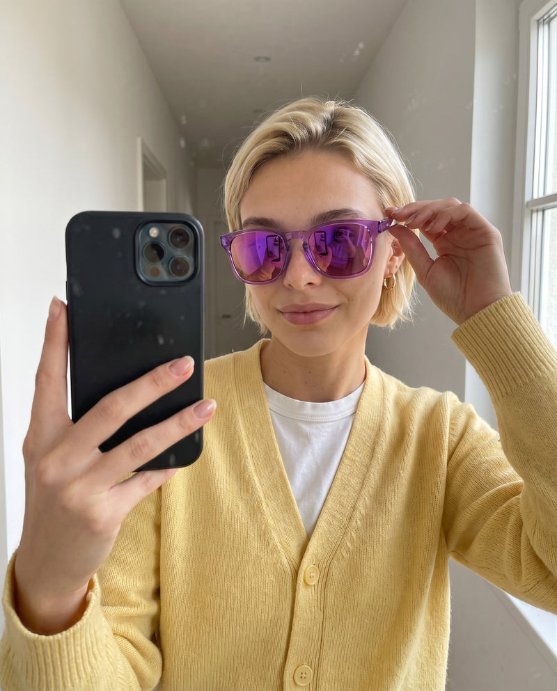 Woman taking a mirror selfie in Vibes Loft purple mirror sunglasses