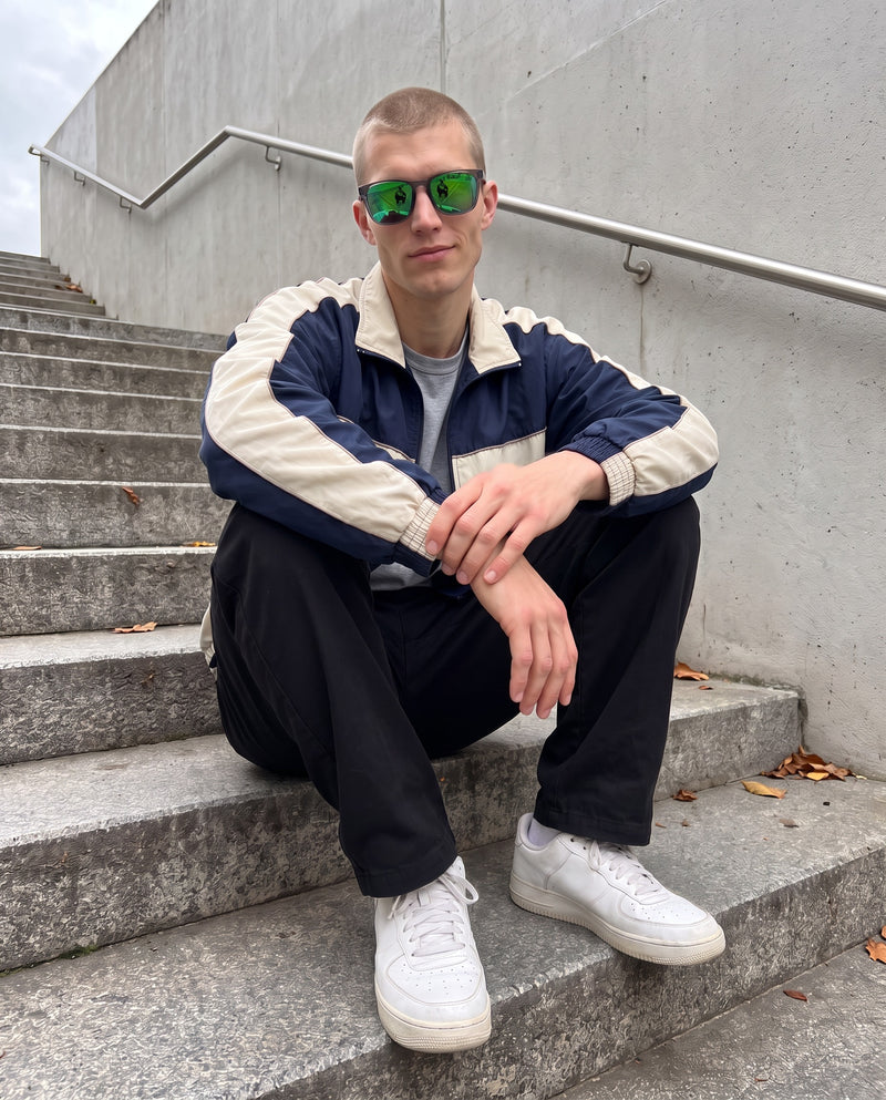 Man sitting on concrete steps wearing Vibes Marlow green mirror sunglasses