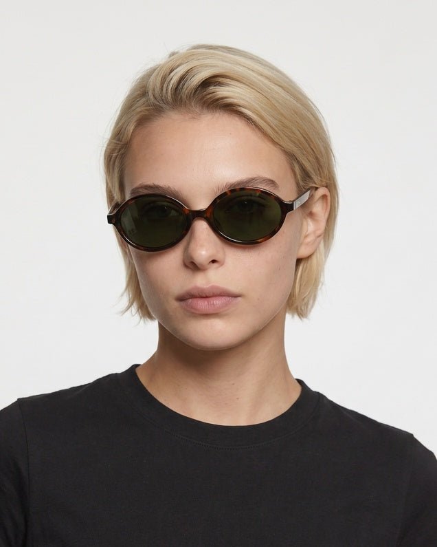 Mojave slim oval metal sunglasses in Green / Tortoise, green lens on tortoise frame, worn by a woman, front view