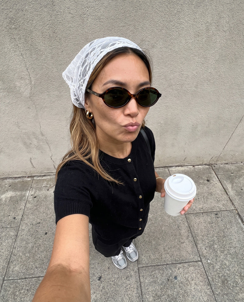 Woman in a lace headscarf taking a street selfie in Vibes Mojave sunglasses