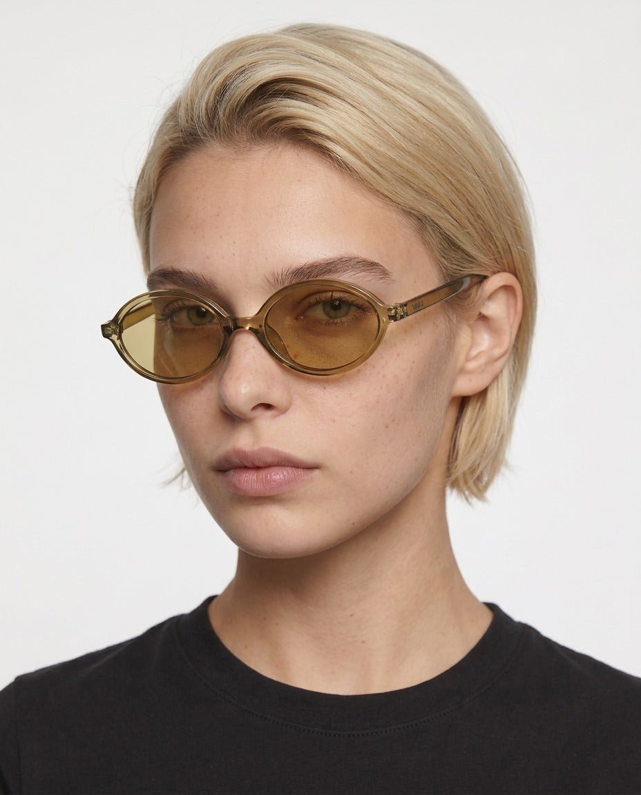 Mojave slim oval metal sunglasses in Gold / Gold, gold lens on gold frame, worn by a woman, front view