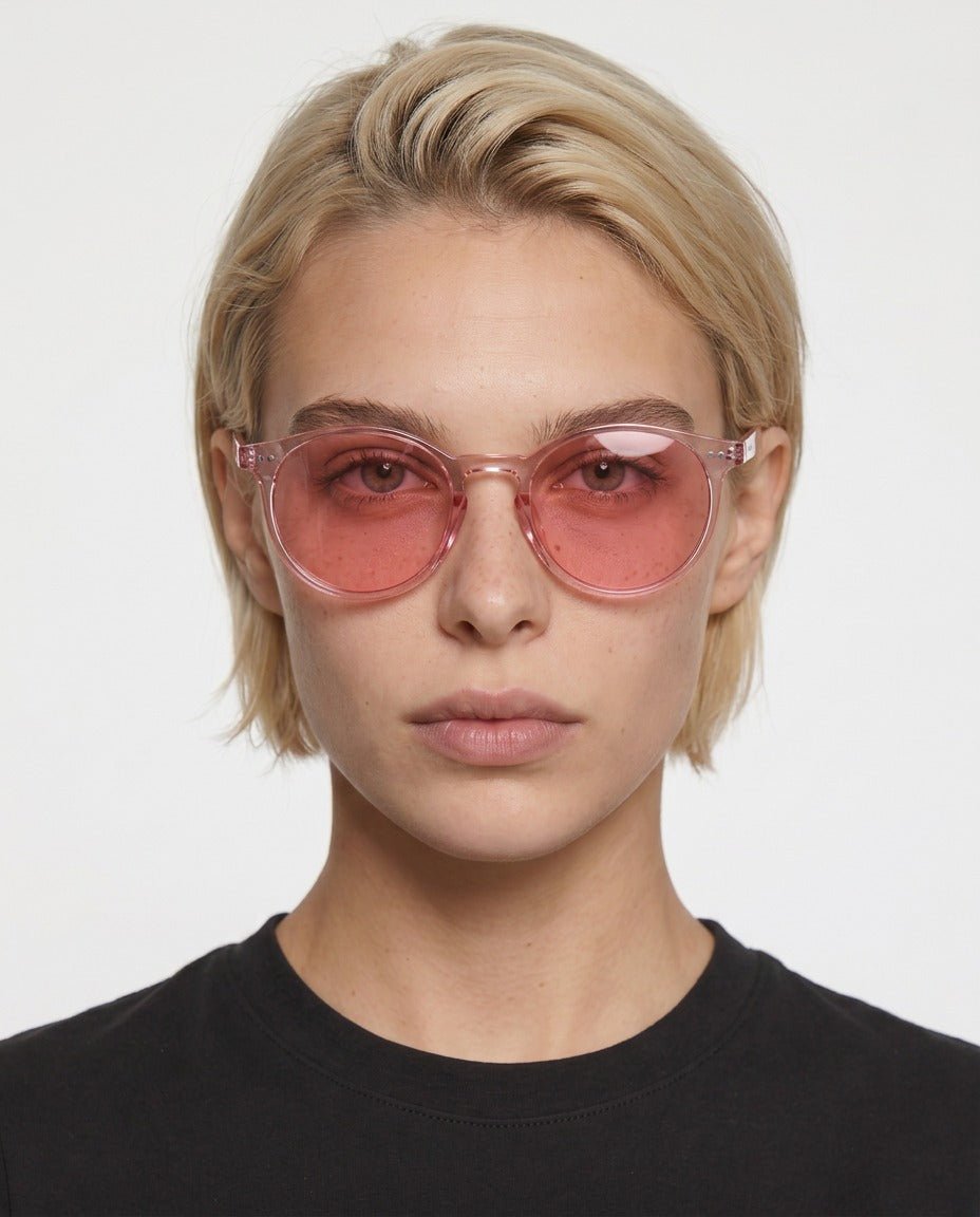 Onyx round retro sunglasses in Pink / Clear Pink, pink lens on clear pink frame, worn by a woman, front view