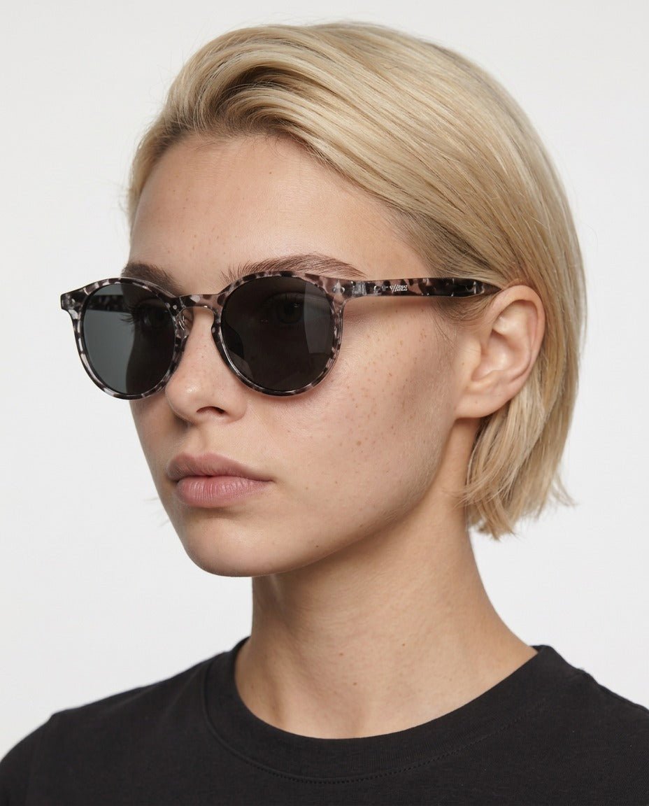 Onyx round retro sunglasses in Black / White Tortoise, black lens on white tortoise frame, worn by a woman, front view