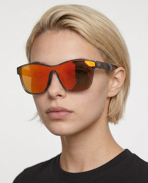 Radar performance wrap sunglasses in Red / Black, red lens on black frame, worn by a woman, front view