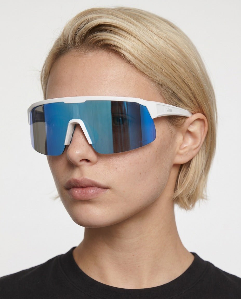 Rialto one-piece shield sunglasses in Blue / White, blue lens on white frame, worn by a woman, front view