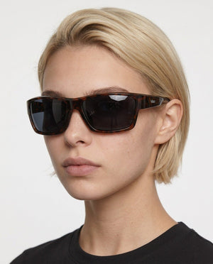 Specter slim wrap sunglasses in Black / Tortoise, black lens on tortoise frame, worn by a woman, front view