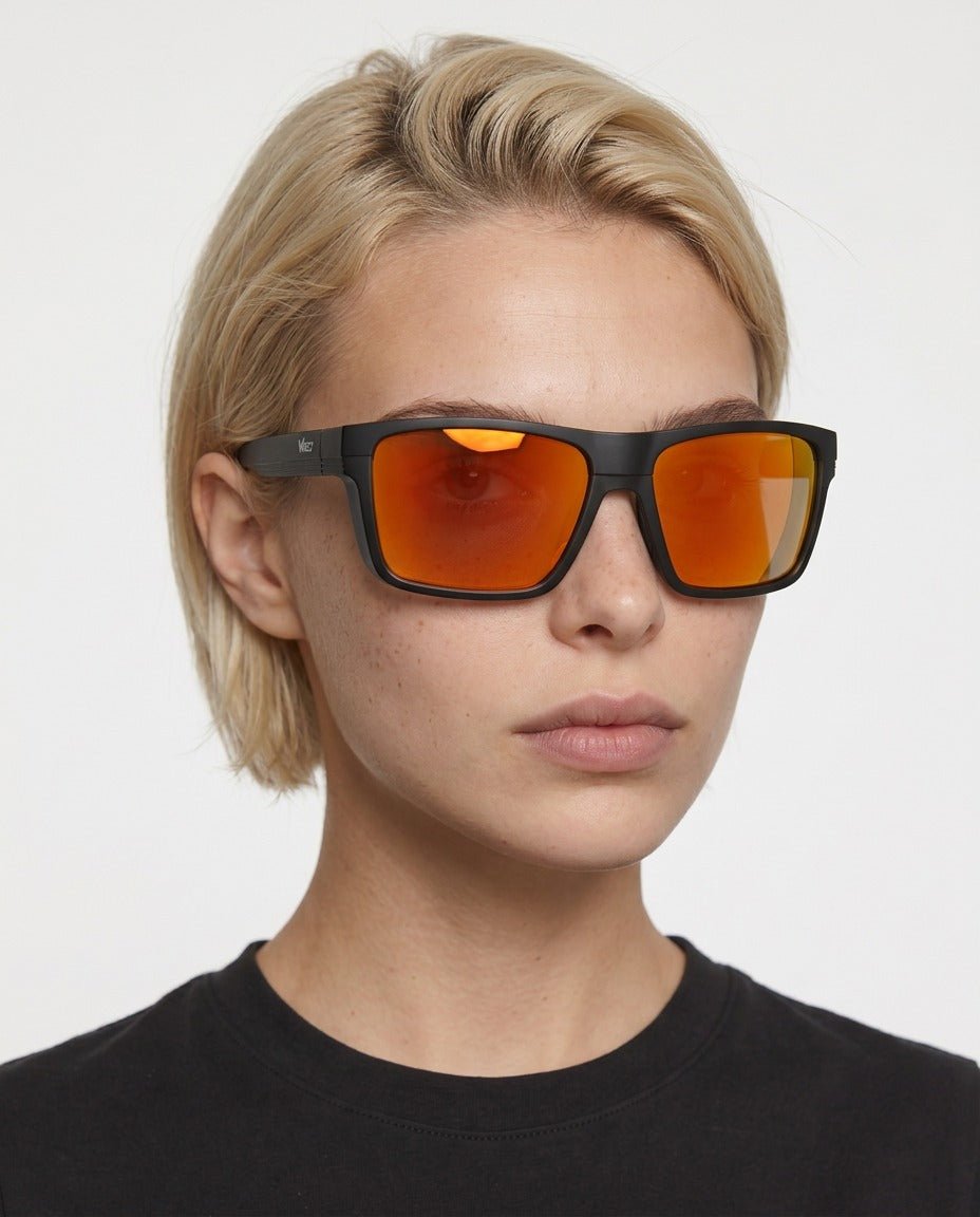 Theo bold wrap sunglasses in Orange / Black, orange lens on black frame, worn by a woman, front view
