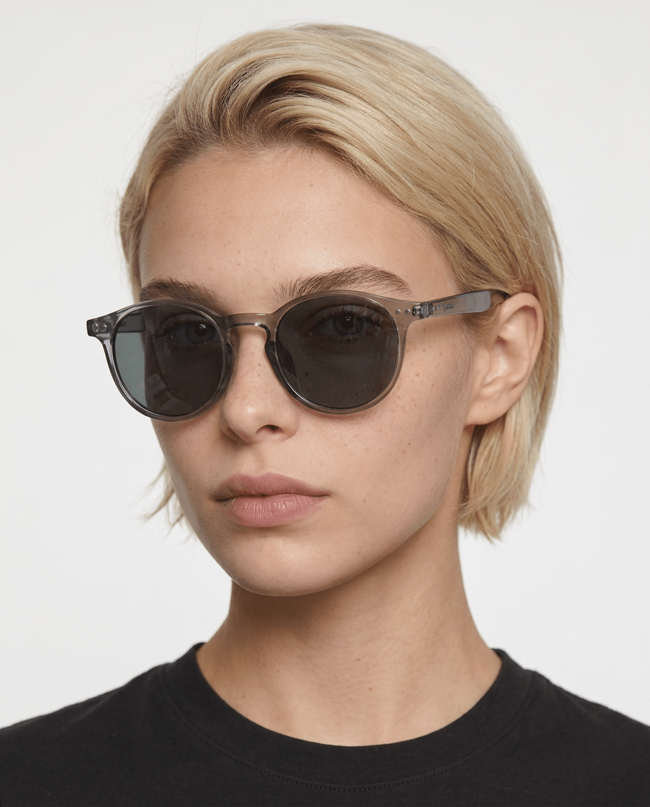 Onyx round retro sunglasses in Black / Clear Grey, black lens on clear grey frame, worn by a woman, front view