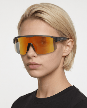 Rialto one-piece shield sunglasses in Orange / Black, orange lens on black frame, worn by a woman, front view
