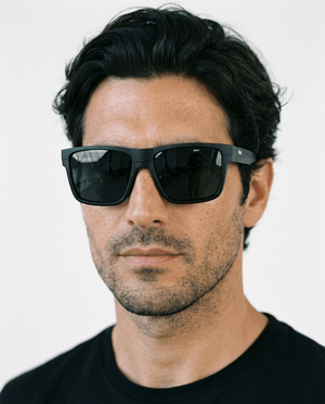 Theo bold wrap sunglasses in Black / Black, black lens on black frame, worn by a man, front view